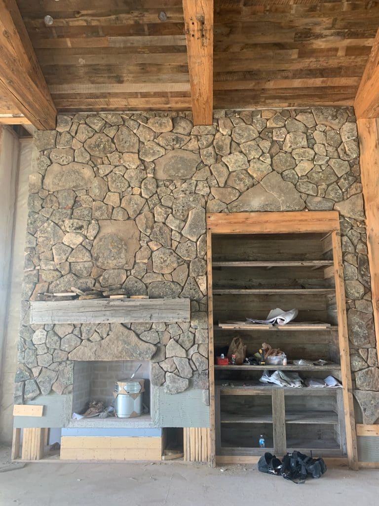 Natural thin stone veneer being installed on a fireplce